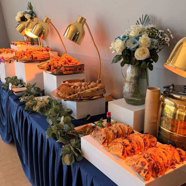 A buffet table with a blue tablecloth, various dishes, and floral arrangements.